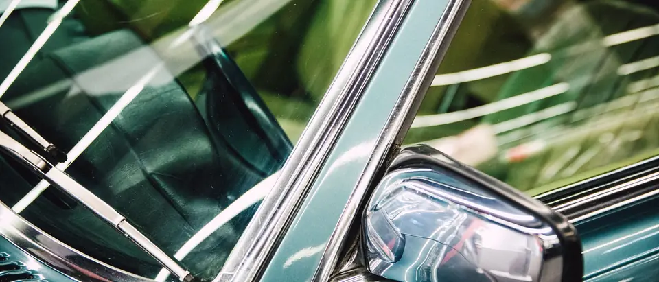 The windshield edge and chrome mirror of a classic car