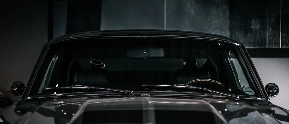 The windshield and wipers of a dark car, seen from the front