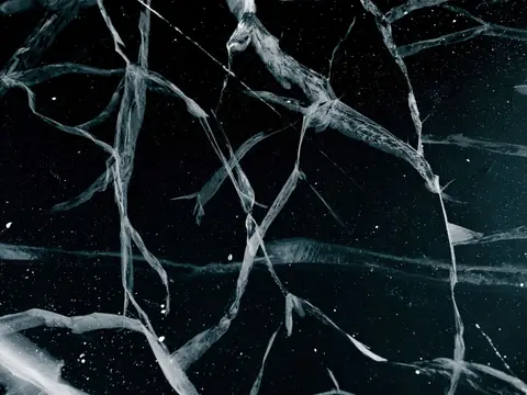 Fracture lines branching across a cracked dark pane