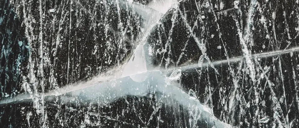 White fracture lines crossing a cracked dark pane