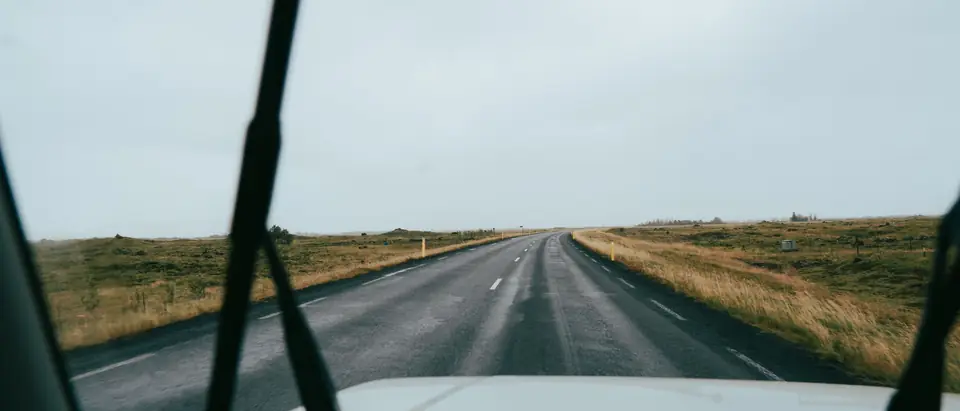 The road ahead through a clean windshield, the wiper arms at rest