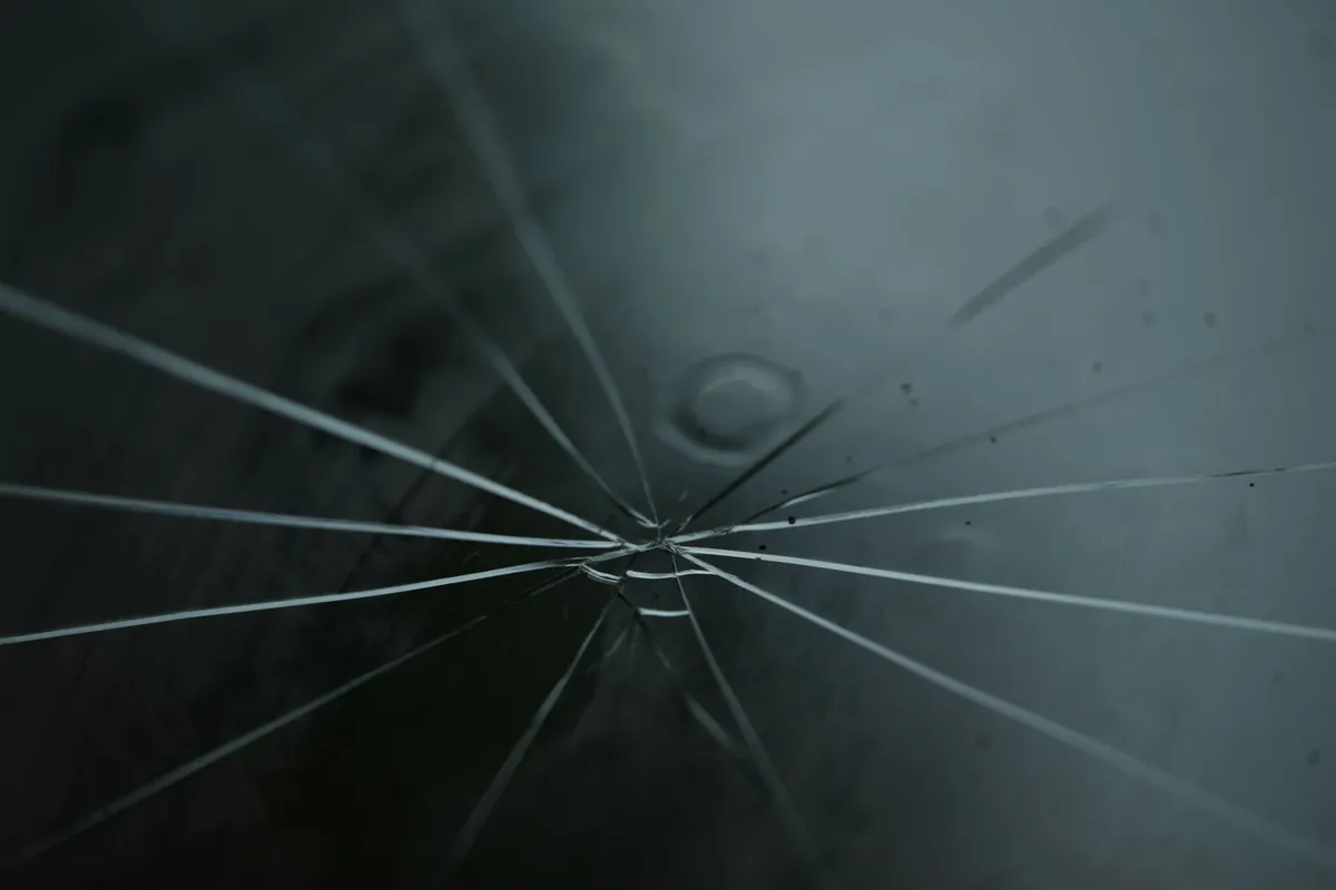 Close-up of cracked auto glass with radiating lines, highlighting the importance of regular checks.